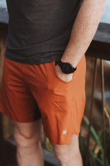 Left view of models hand in the side pocket of rust Rep Shorts. Athleisure shorts with pockets.