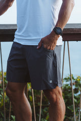 Model with his hands in pockets of charcoal Rep shorts. Men's grey athleisure shorts.