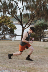 Model doing lunges in rust Rep Shorts. Men's workout shorts with flexible fabric for any movement.