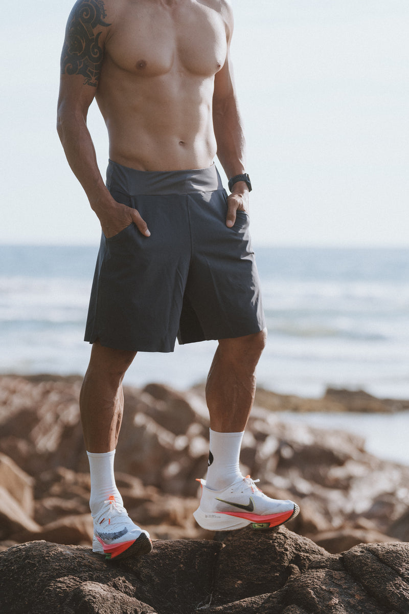 Model wearing charcoal Arvo Shorts by the ocean.