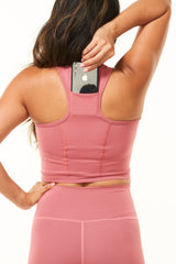 Model placing phone in back pocket of Nantucket Core Crop. Women's running top with pockets.