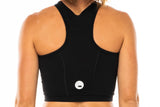 Back view women's Black Core Crop. Black form-fitting athletic top with reflective logo.