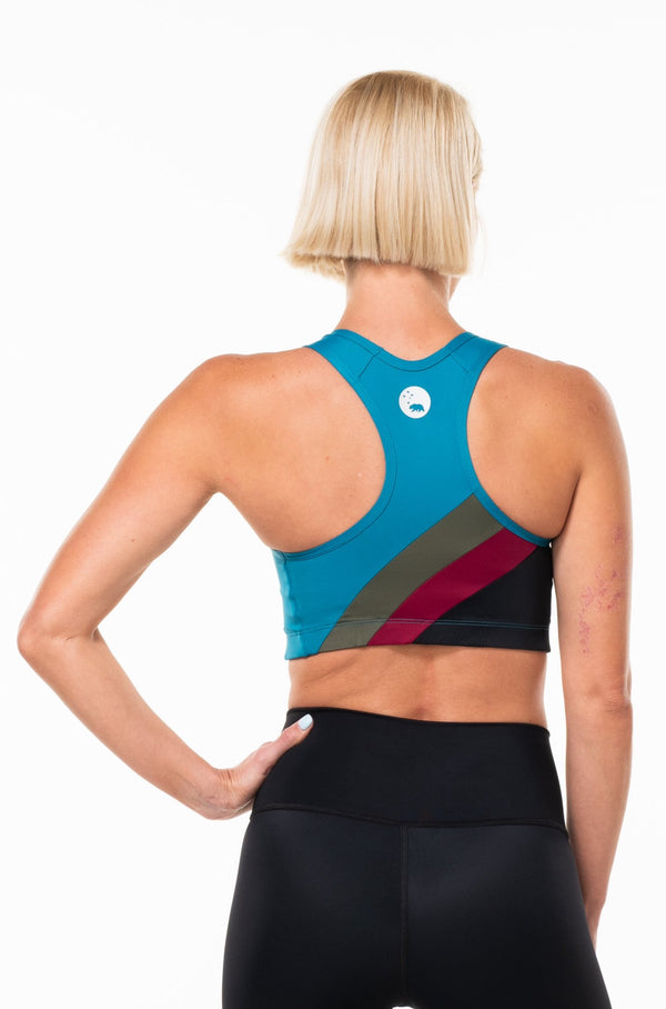 Back view Racergril bra. Blue sports bra with green, red, and black stripes. Sports bra with mesh panel for ventilation.