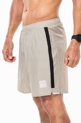 Left view men's Noosa Run Short. Tan run shorts with vertical black stripe and reflective logo.