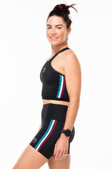 Left view model wearing black athleisure shorts. Women's mid-thigh shorts that are quick drying and breathable.