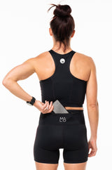 Model placing a phone in the back pocket of black running shorts. Workout shorts that hold your belongings