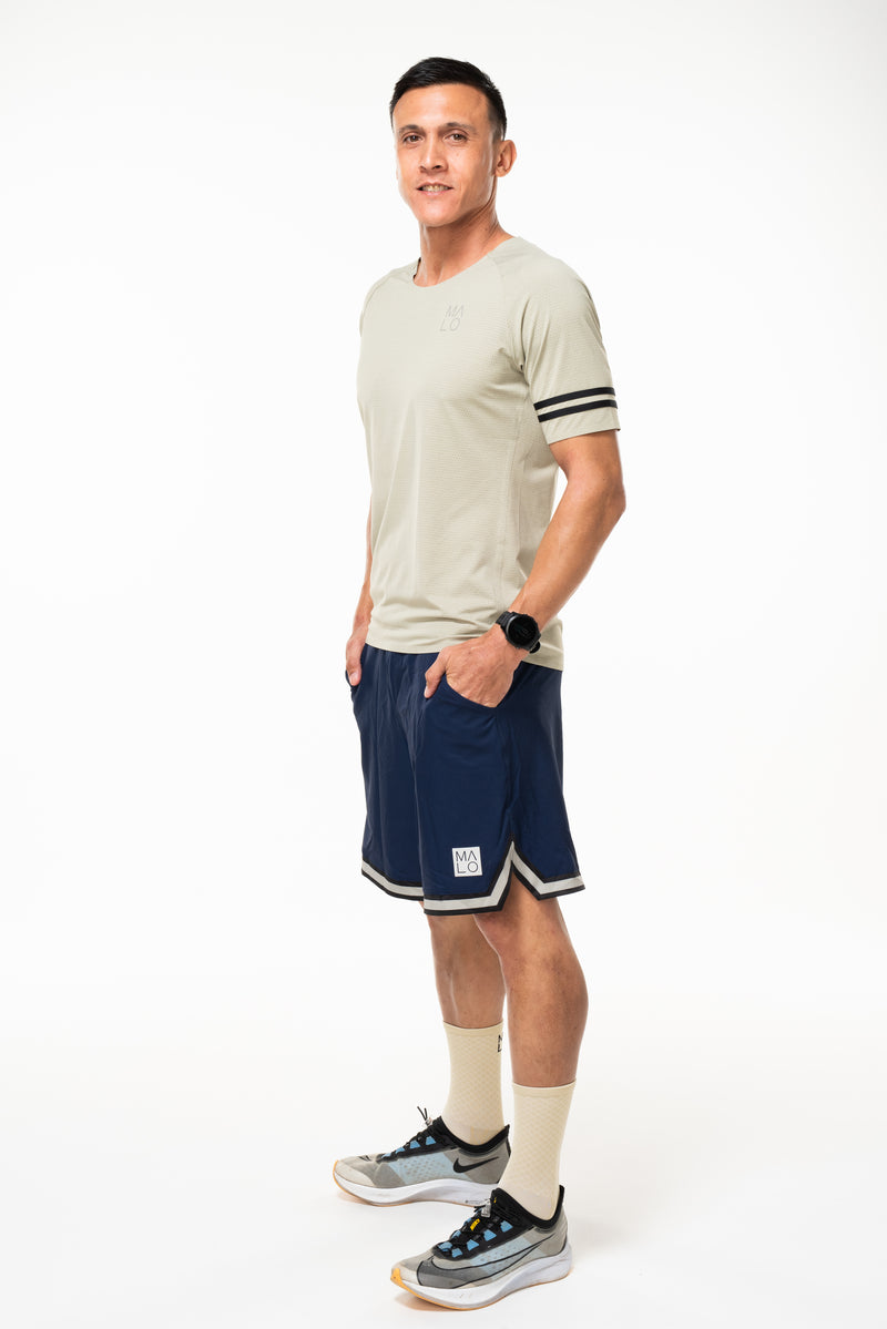 Model wearing navy Arvo Shorts with matching tan tee. Above the knee navy athleisure shorts. 