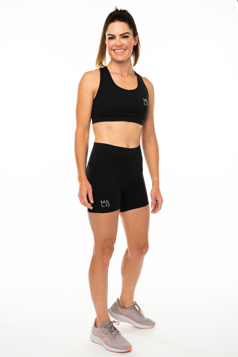 Model wearing Black Little Bit Longer Shorts. Women's mid-length workout shorts that are breathable.