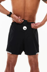 Model placing phone in back pocket of Black Noosa Run Short. Lined running shorts with pockets