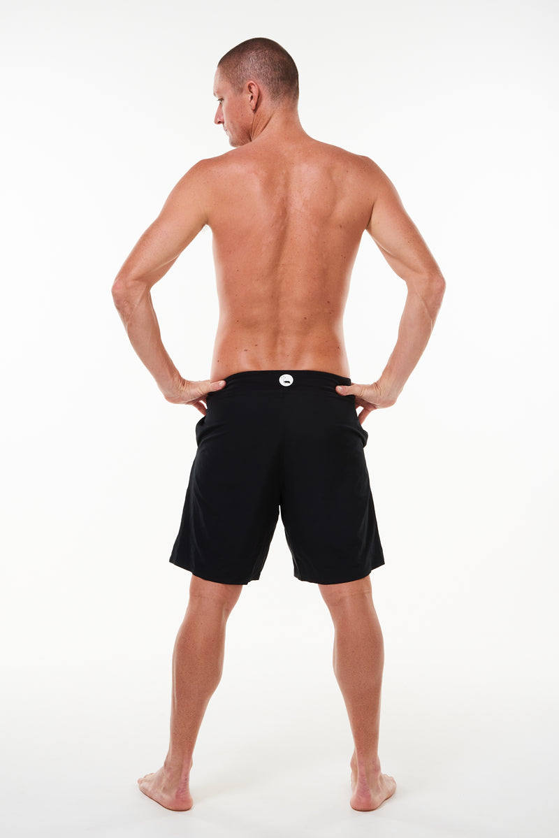 Back view of Arvo Shorts. Lined above the knee black workout shorts with reflective logo on waistline.