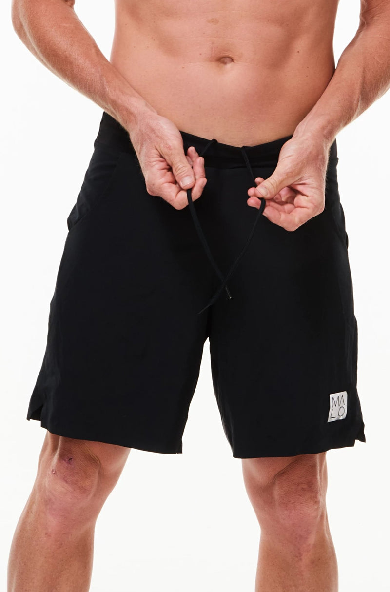 Model tying drawstring in Arvo Shorts. Black workout shorts with comfortable and adjustable waistline.
