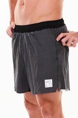 Left view men's Noosa Run Short. Black run shorts with reflective logo and stripe on left thigh.