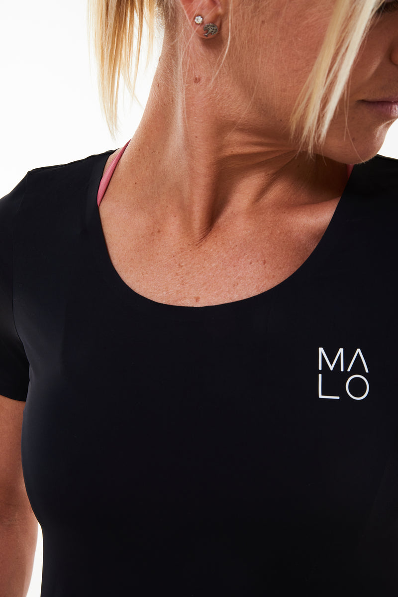 Close view of Women's Edge Performance Tee. Black workout shirt with white 'MALO' logo on left side.