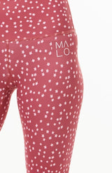 Close view left hip 7/8 leggings. Pink leggins with white 'MALO' logo. Pink daisy print pants.