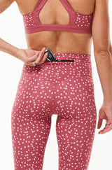Model placing keys in the back pocket of left leg in pink 7/8 leggings.