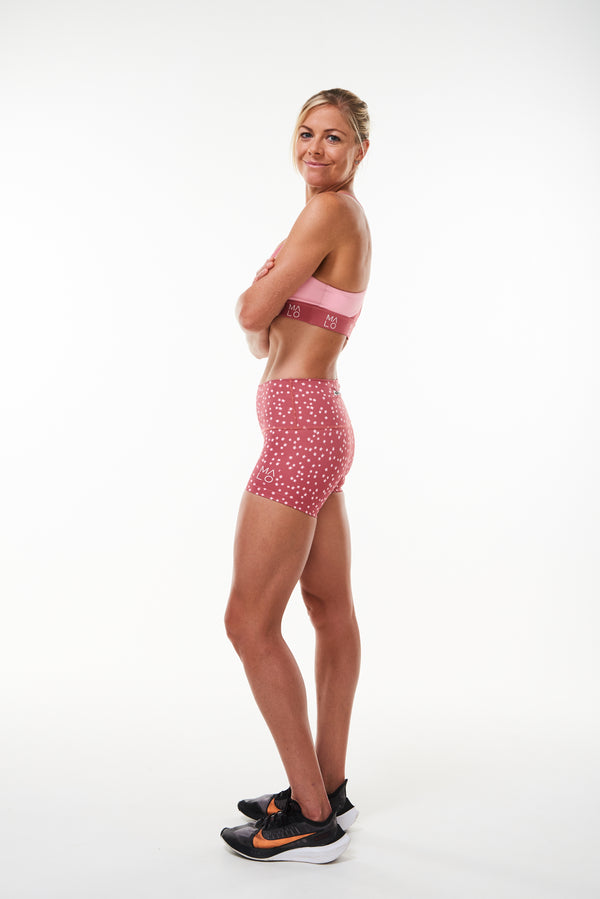 Model wearing Nantucket Bloom PR Shorts. Women's pink athleisure shorts with daisy print.