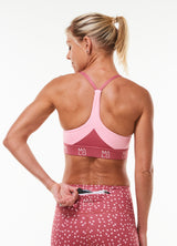 Model placing keys in back pocket of PR Shorts. Pink workout shorts with zipper pocket in waistband.