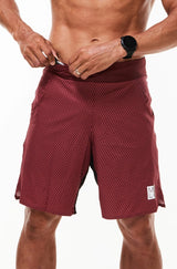 Model placing keys in small waistline pocket of Arvo Shorts. Red running shorts with pockets.